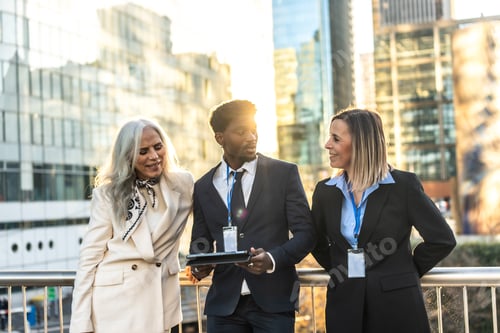 Preview: Diverse business professionals discussing work using tablet in city