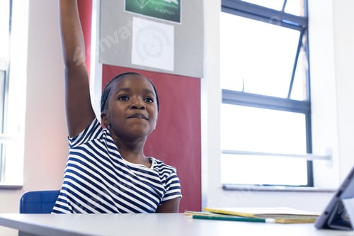 Preview: In school, african american girl raising hand in classroom, eager to answer question