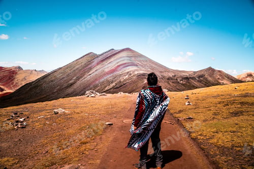 Preview: Person in poncho gazing at Rainbow Mountain in Peru