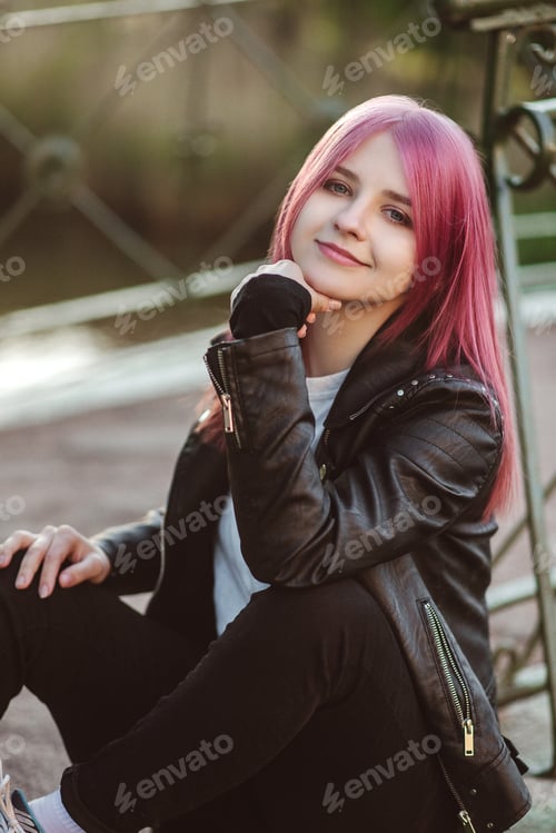 Preview: A beautiful girl with pink hair is sitting on a bridge