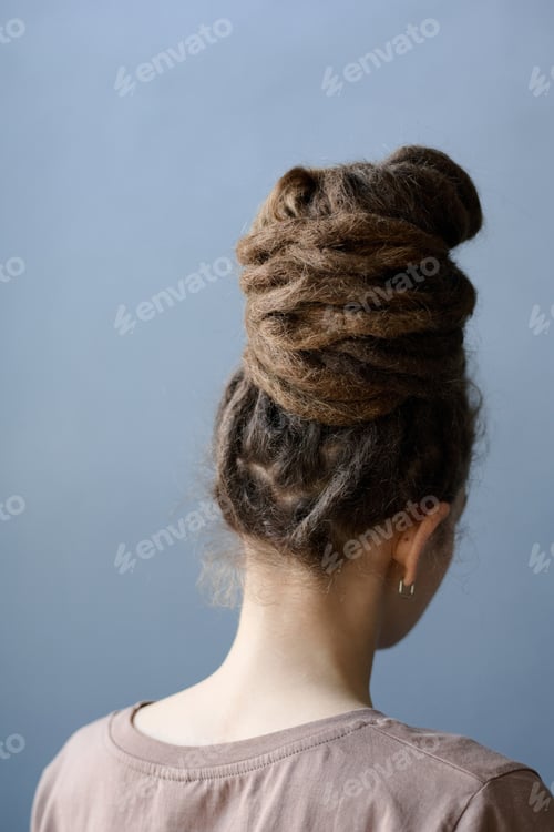 Preview: Back View of Woman with Dreadlocks in Bun Facing Away on Grey