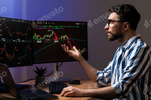 Preview: Crypto trader looking at computer monitor, working online with crypto chart sitting in office