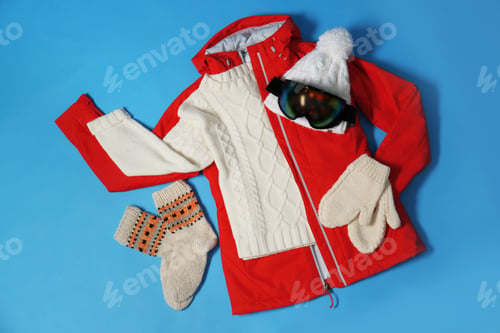 Preview: Stylish winter sport clothes on light blue background, flat lay