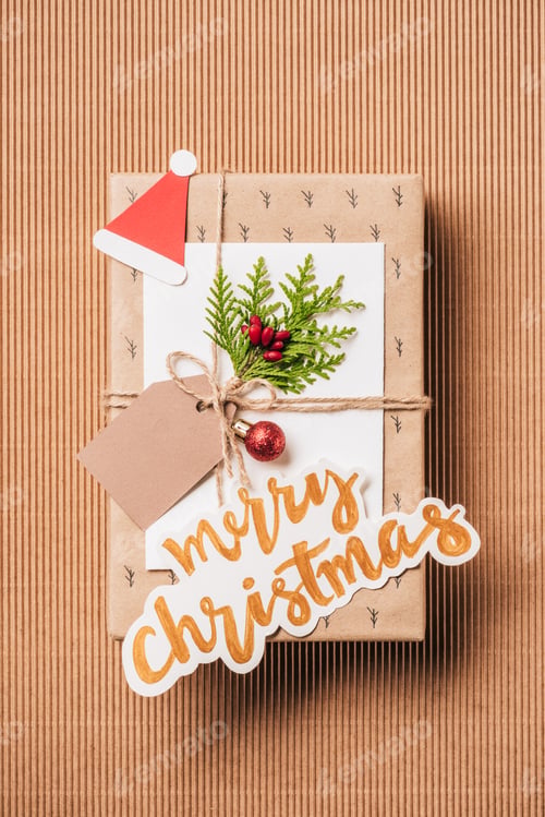 Preview: flat lay with gift box with baubles, evergreen branch and merry christmas lettering on surface