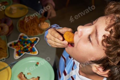 Visualização: Caucasian Child Boy Eating Chicken Nugget during Festive Party Gathering