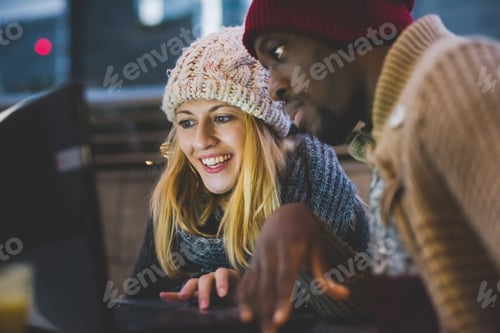 Preview: Couple using laptop outdoors at dusk