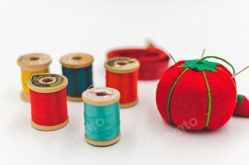 Preview: Vintage bright colorful antique sewing notions on a white background, thread spools and pin cushion