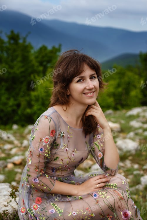 Preview: Young happy woman in long dress on the mountainside.
