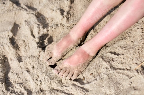 Preview: Sunlit sand-covered feet at beach