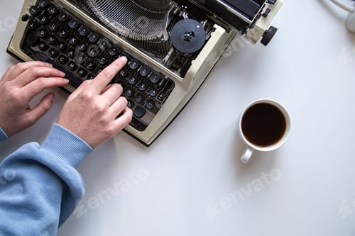 Preview: Woman's hand typing on a vintage typewriter top view.