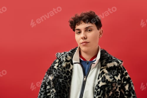 Preview: Stylish young man showcases trendy fashion against vibrant red backdrop