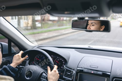 Preview: Woman drive a car reflects in back view mirror.