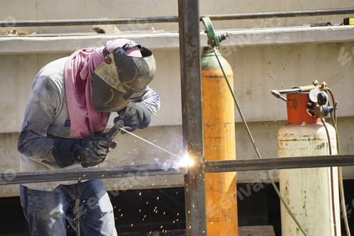 Preview: Worker welding iron at the construction area under the sunlight at daytime - industrial concept