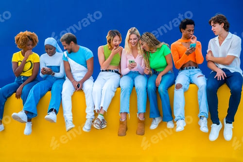 Preview: Friends sitting on a colorful wall and using phones