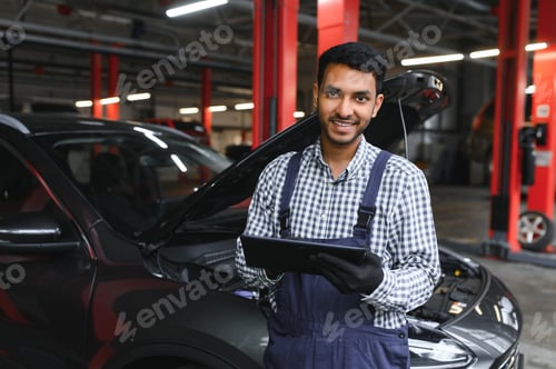 Preview: Indian car mechanic standing and working in service station.