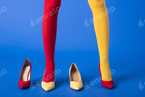 Preview: cropped view of stylish model in yellow and red tights and shoes posing on blue