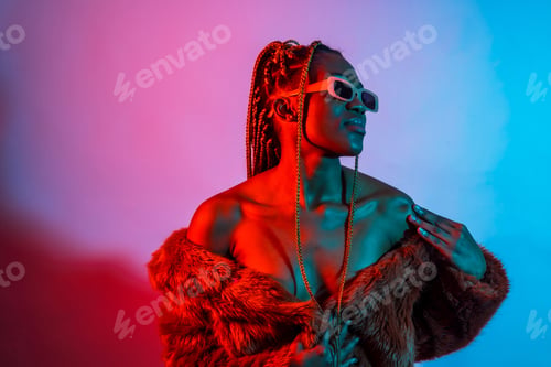 Preview: Attractive black ethnic woman with braids with red and blue led lights, urban studio shoot