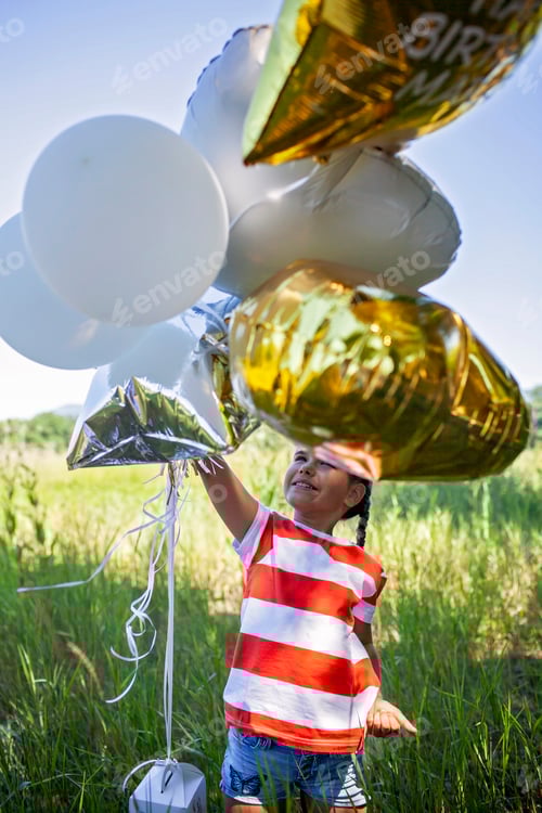 Preview: Photo of a smiling birthday girl riding a scooter down a rural road at golden hour
