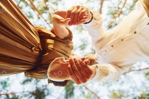 Preview: View from below. Happy couple is outdoors in the forest at daytime