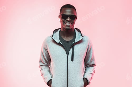 Preview: African guy wearing casual clothes, glasses and wireless earphones