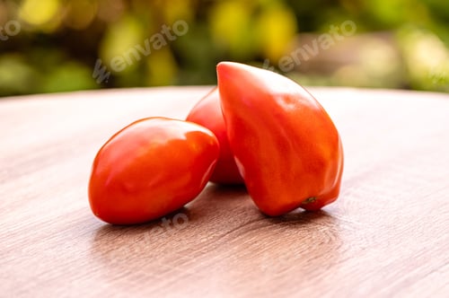 Preview: fresh red tomatoes on a wooden table against the background blur green leaves bokeh, close-up