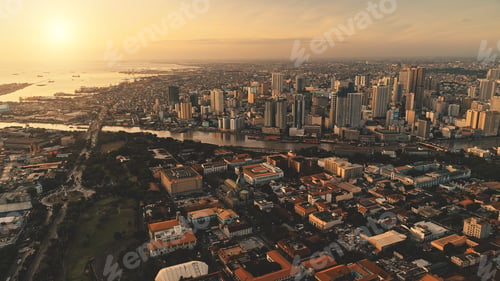 Preview: Sunrise over cityscape with green park at river shore aerial. Modern skyscrapers at business center