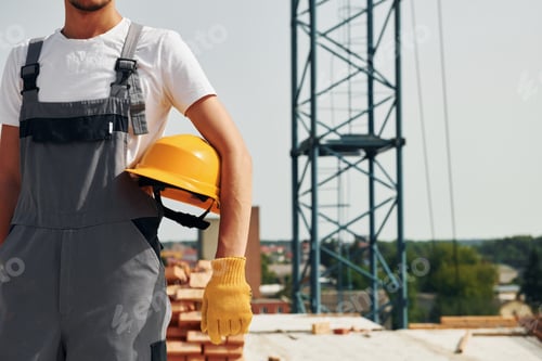 Preview: Close up view. Young construction worker in uniform is busy at the unfinished building