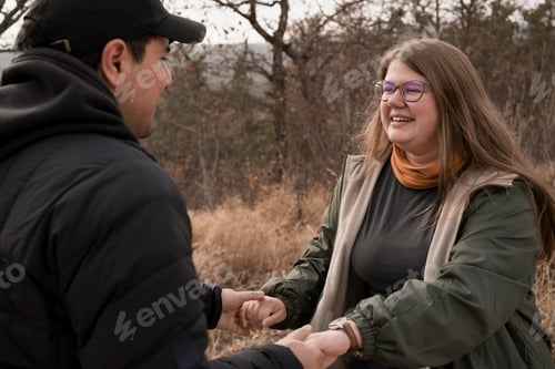 Preview: Happy young adult couple in love smiling holding hands and looking to each other outdoors in autumn