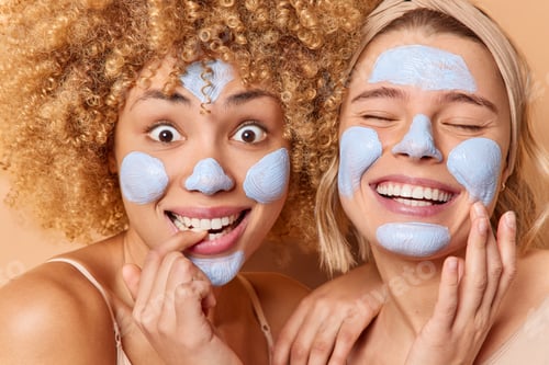 Preview: Headshot of positive pleased young women apply beauty masks smile toothily undergo skin care treatme