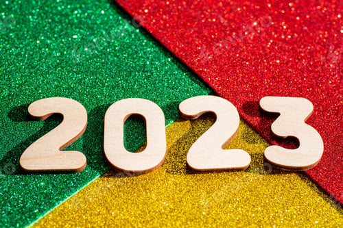 Preview: Wooden numbers 2023 on multicolored trending red, green, gold glittering starry background