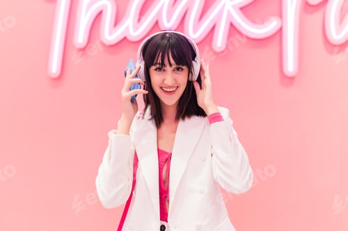 Preview: Cheerful Asian woman listening to music with raised hands