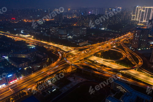Preview: Aerial view of an intersection illuminated by orange-yellow street lights at night.