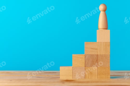 Preview: Stacked wooden blocks on wooden desk against blue background