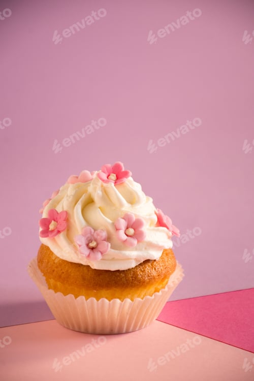 Preview: Appetizing cupcake with a pink frosting and decorative sprinkles on a pink surface