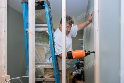 Preview: Building a home using an air hammer to nail wooden beams to framework of house during construction