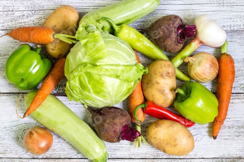 Preview: Close up of various colorful raw vegetables on white wooden background.