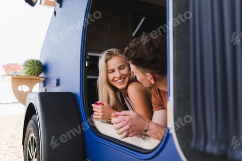 Preview: Happy young couple lying together in a van, enjoying vacation time together.