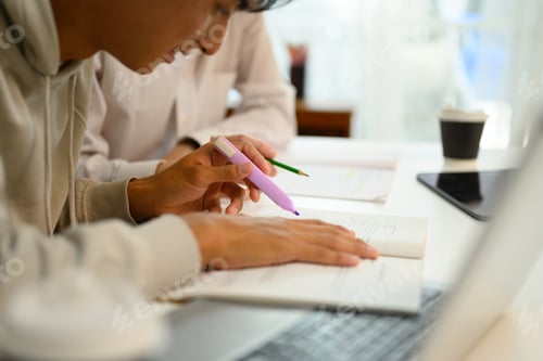 Preview: Close up shot of student highlighting important text with a marker while studying with his tutor