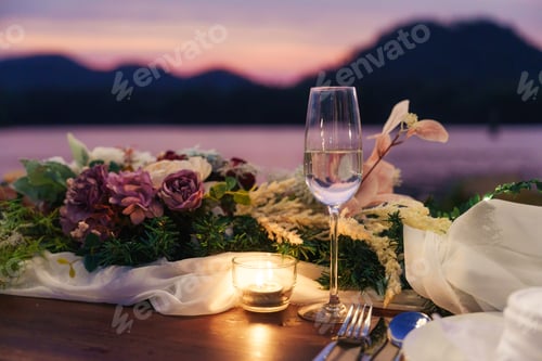 Preview: Rustic style dining table with flower, wine glass, candle decoration at dinner by the river