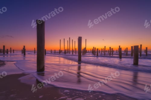 Preview: A seascape during sunset. Pillars on the seashore. Bright sky during sunset.