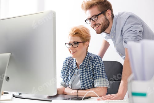 Preview: Smiling young woman and man at desk in office