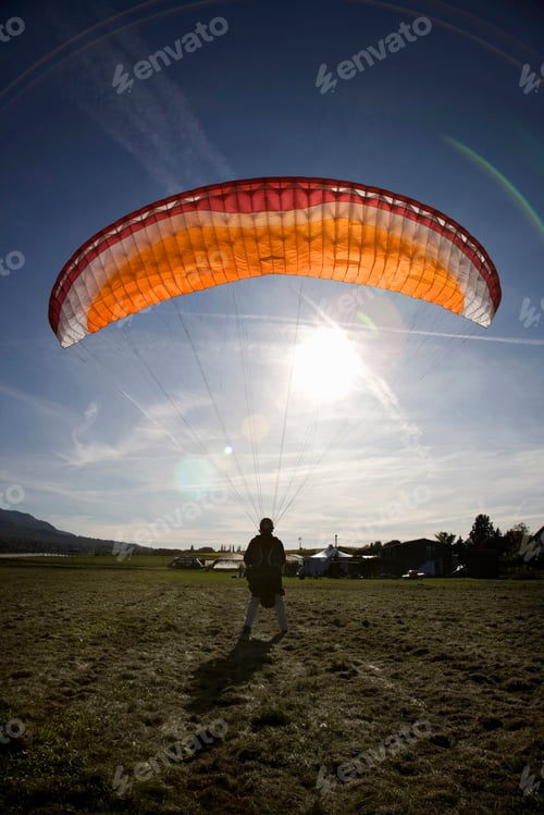 Preview: Mature male paraglider landing with parachute, Mount Saleve, Geneva, Switzerland