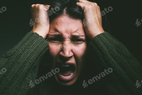 Preview: Studio shot of a young woman experiencing mental anguish and screaming against a black background