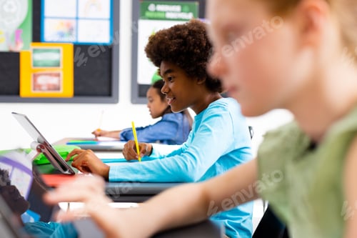 Preview: Happy diverse schoolchildren sitting at desks in school classroom