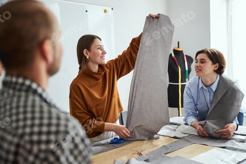Preview: Joyful tailor spreading textile cloth in workshop