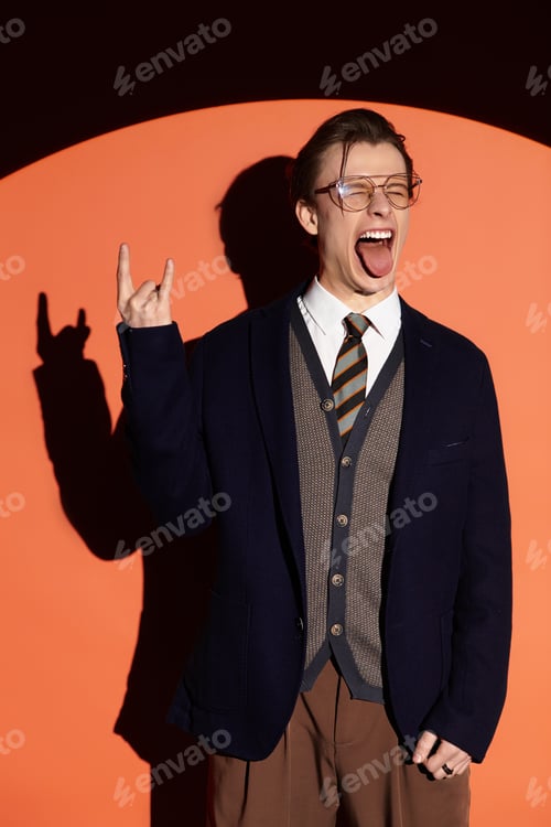 Preview: Stylish teenager poses confidently against a vibrant orange backdrop expressing youth culture