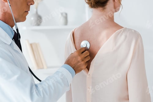 Preview: cropped view of doctor using stethoscope while examining woman in clinic