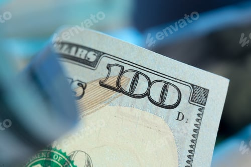 Preview: Close-up of a one hundred dollar bill held in hand with soft background