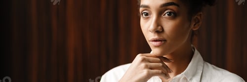 Preview: Young black woman standing and looking aside indoors