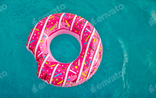 Preview: bright pink inflatable ring floating in swimming pool. Vacation concept with copy space